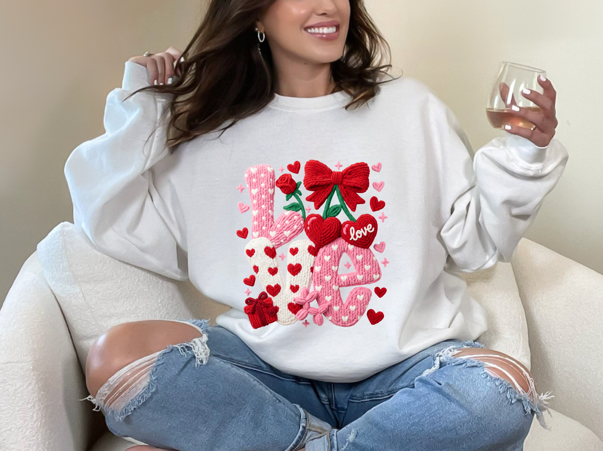 Person wearing a white sweatshirt with decorative text and graphics, sitting on a couch.